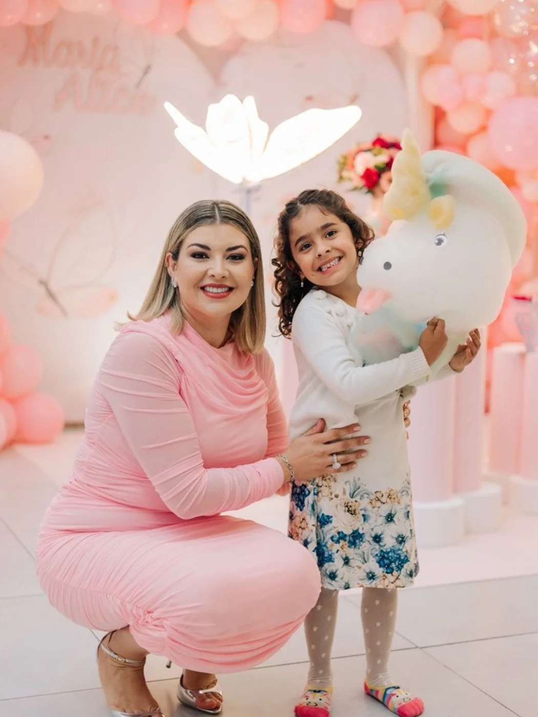 Mãe e filha segurando esculturas de algodão doce artístico em festa decorada